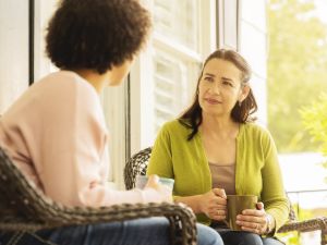 A woman with a hearing aid watches a woman talking and uses lipreading to help her understand.
