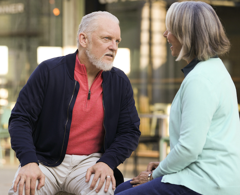 A man strains to hear a person talking.
