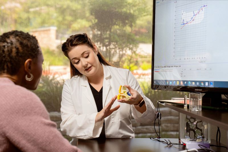 A woman at a hearing clinic talks to her audiologists.