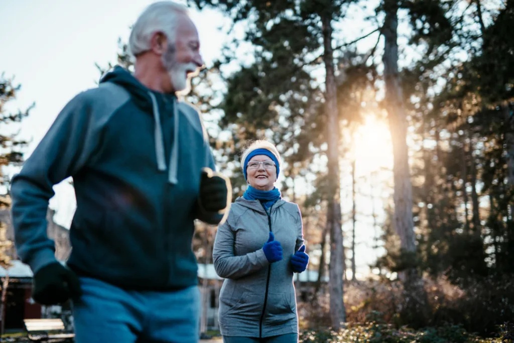 an older gentleman and woman jogging together in the winter