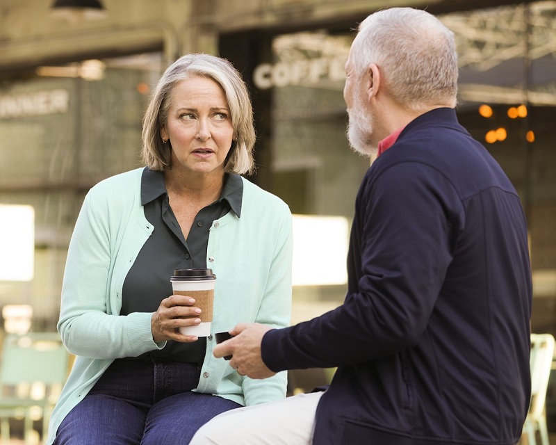 A woman struggles to hear a man talking to her, because her ears are stuffy.