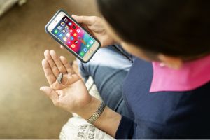 A woman connects her new hearing aids to a smartphone.