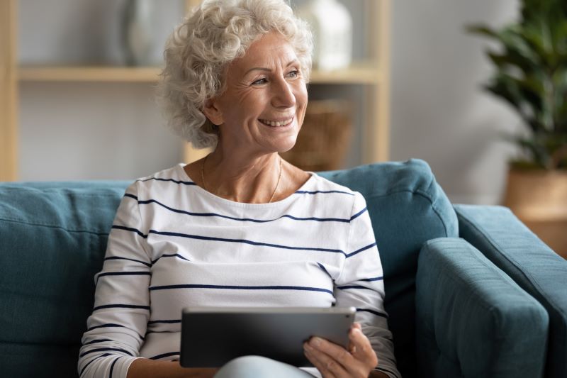A woman sitting on her couch, smiling.