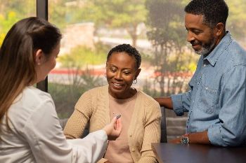 A woman gets hearing aids with her partner standing nearby.