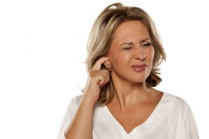 Image shows a woman scratching her itchy ear. Scratching your ear can make itchiness worse.  