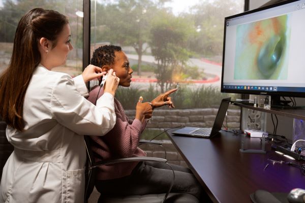 A woman receives an otoscopic ear exam.