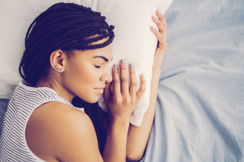 A woman sleeps in bed.