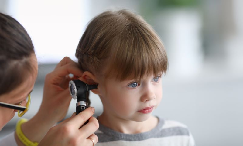 A young girl receives an ear exam to look for infection.