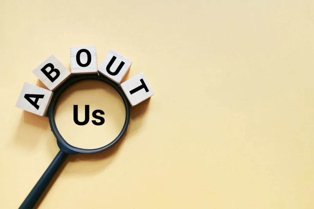 the word "about" spelled out using letter blocks curved around a magnifying glass focusing on the word "us"