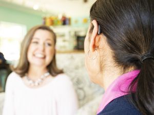 A woman with a hearing aid talks to a friend.