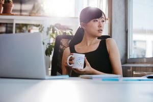 A woman at a desk, thinking.
