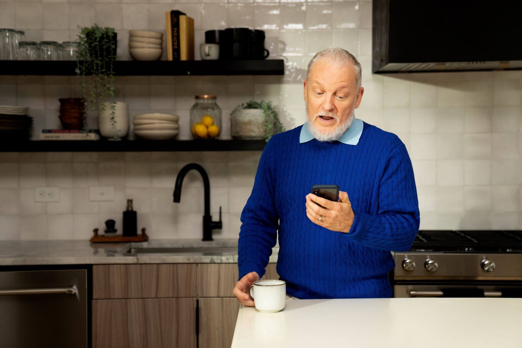 A man talks on the phone in his kitchen.
