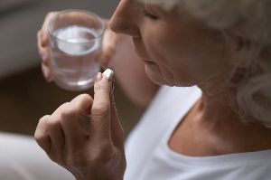 A woman takes a pill.