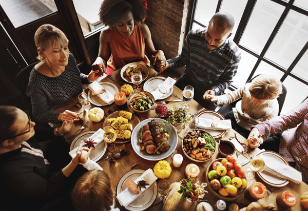 people sitting for meal holding hands