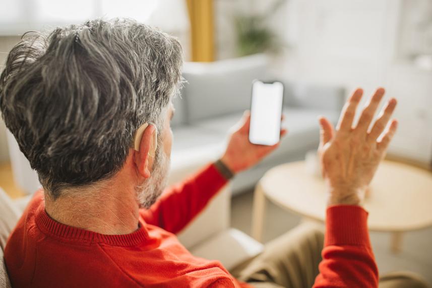Man with a hearing aid looking at a phone